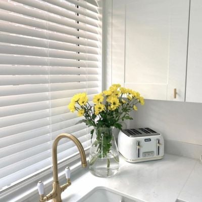 White wooden Venetian blinds in a white marble kitchen